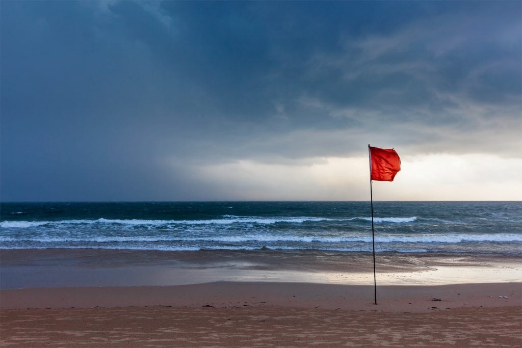 View of Beach with Storm Approaching with Warning Flags